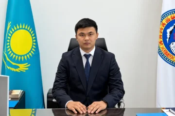 Мужчина в деловом костюме на фоне флагов Казахстана и Алматы